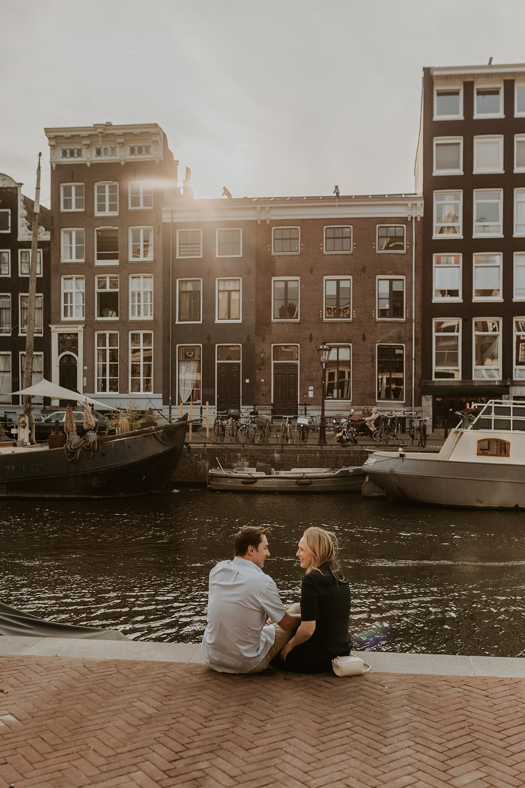 Tourist couple enjoying sunset photoshoot in Damrak Amsterdam